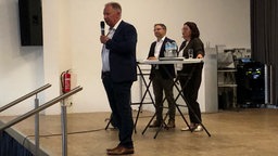 Landrat Pusch bei der Bürgerversammlung mit Mikrofon auf der Bühne