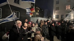 Viele Menschen stehen im dunklen auf der Straße mit Schildern