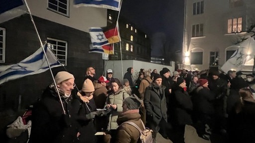Viele Menschen stehen im dunklen auf der Straße mit Schildern