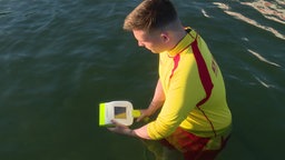 Man sieht, wie ein Wasserretter das Gerät bedient