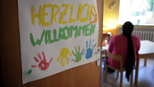 Eine junge Frau aus Nigeria sitzt im Spielzimmer des internationalen Frauenhauses in Düsseldorf. Im Vordergrund sind 