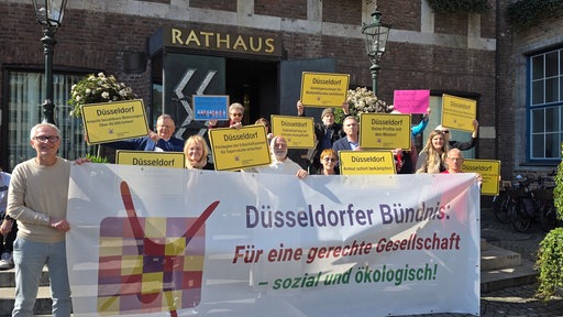 Menschen mit gelben Schildern und einem großen Banner auf einer Treppe