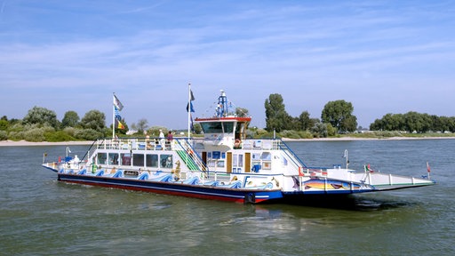 Auf dem Foto ist eine blau-weiß-rote Fähre, die auf dem Rhein fährt.