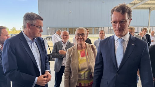 Drei Männer und eine Frau im Anzug, darunter Ministerpräsident Wüst