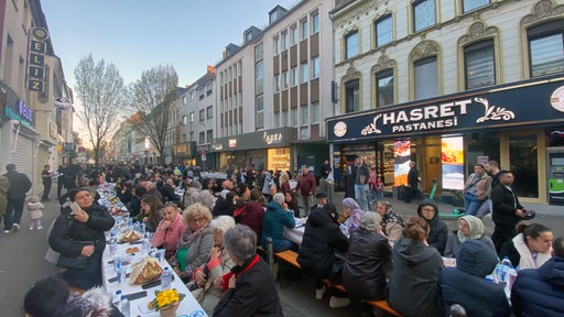 Viele Menschen haben sich an Tischen auf der Keupstraße versammelt. 
