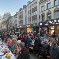 Viele Menschen haben sich an Tischen auf der Keupstraße versammelt. 