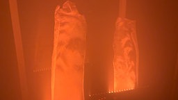 Ein vernebleter Raum und Stoff der beleuchtet wird, so dass er wie eine Flamme aussieht