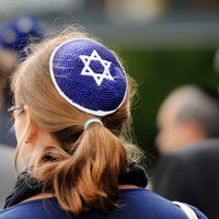 Eine junge Frau mit Kippa nimmt an einer Demonstration teil.