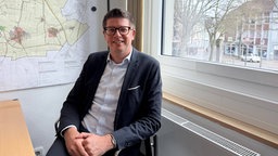 Ein Mann mit dunkem Jackett sitzt in einem Büro