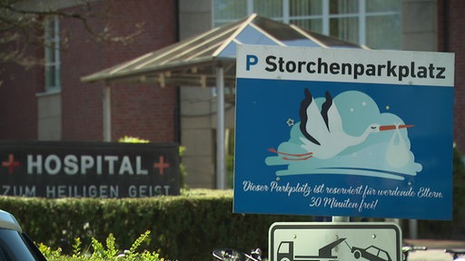 Zwei Schilder stehen nebeneinander. Auf dem linken Schild ist der Name der Klinik in Kempen zu lesen, auf dem rechten steht Storchenparkplatz für werdende Eltern