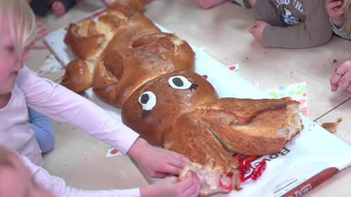Kinder brechen Stücke des riesigen Osterhasen ab - angefangen bei den Ohren.