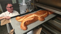 Der Hase wird aus dem Ofen gezogen. Er ist aufgegangen und braun gebacken.
