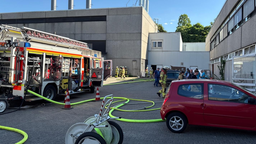 Auf dem Bild sind mehrere Feuerwehrleute, ein großer Leiterwagen der Feuerwehr vor einem Gebäude.