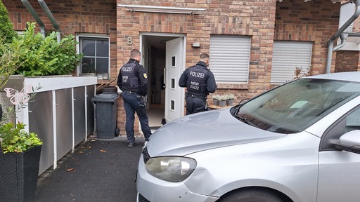 Zwei Polizisten in Uniform vor einem Hauseingang