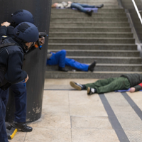 Zwei bewaffnete Polizisten blicken auf eine Treppe, auf der Menschen liegen.