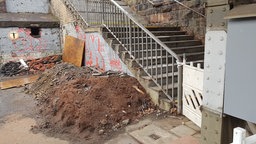 Erd- und Schutthügel neben einer abgesperrten Treppe