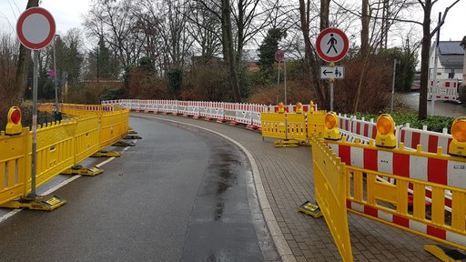 Entlang einer Straße stehen Baustellen-Absperrungen und Warnschilder