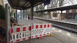 Ein Bahnsteig neben Gleisen ist durch Barken abgesperrt