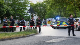 Polizisten stehen vor einer Absperrung