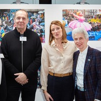 Vier Menschen posieren vor aufgestellten Wänden mit Fotos