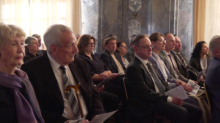 Zuhörer sitzen beim Festakt zum Jubiläum der Neugründung der Jüdischen Gemeinde in Düsseldorf nebeneinander.