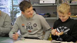 Sawyer (rechts) malt gemeinsam mit einem anderen Kind im Jugentreff in Mönchenglabach.