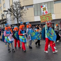 Eine Fußgruppe im Veilchendienstagszug in Mönchengladbach mit einem Schild "Gladbachs Zug gefällt gewiss der ganzen Welt"