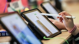 Ein Kind bedient ein Tablet mit einem Stift. (Symbolfoto)