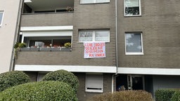Banner mit Aufschrift "Keine Drogendealer auf Schulwegen der Kinder" hängt an Hauswand