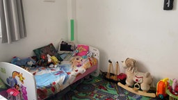 Ein Kinderbett steht in einer Ecke des Zimmers, rundherum liegt Spielzeug.