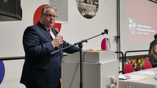 Lutz Schade mit Mikrofon auf einer Bühne.