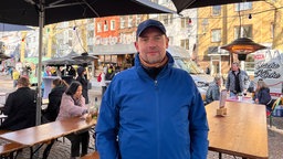 Mann in blauer Jacke auf dem „Meet & Eat“ Feierabendmarktes am Rudolfplatz.