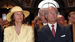König und Königin von Schweden sitzen nebeneinander auf Stühlen