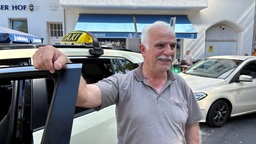Taxifahrer vor seinem Taxiwagen