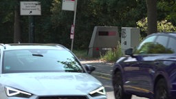 Blitzeranhänger am Straßenrand, Autos fahren vorbei