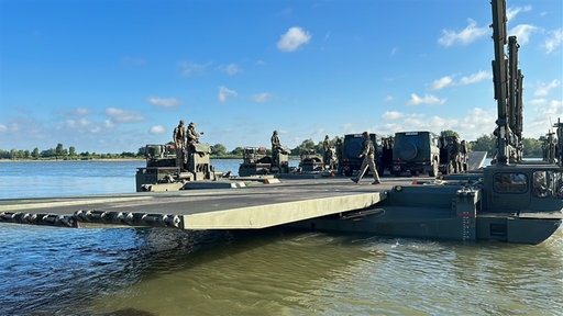 Mehrere schwimmende Militärfahrzeuge transportieren Autos über den Rhein