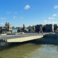 Mehrere schwimmende Militärfahrzeuge transportieren Autos über den Rhein