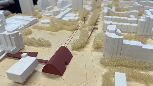 Ein Modell eines Stadtbildes: Alle Häuser sind weiß bis auf ein rotes Gebäude