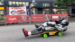 Zwei Fahrer auf Bobbycars, auf dem Rücken liegend