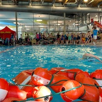 Ein Mann schwimmt in einem Schwimmbecken, im Vordergrund liegen mehrere Rettungspuppen