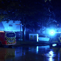 Das Bild zeigt einen Einsatzwagen der Polizei und des Notarztes auf einer dunklen Straße.