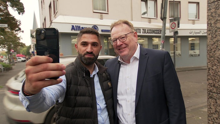 Der neue Kölner Oberbürgermeister Burmster der SPD macht mit einem Mann ein Selfie auf der Kalker Hauptstraße 