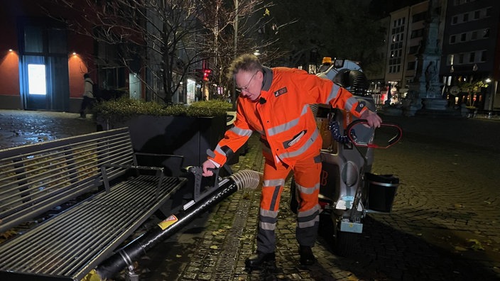 Der gewählte Oberbürgermeister von Köln, Torsten Burmester, trägt orange AWB-Arbeitskleidung und saugt Müll weg