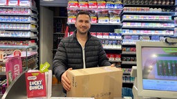 Kiosk-Mitarbeiter Malik kümmert sich in der Kölner Innenstadt um die Paketannahmen.