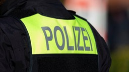 Symbolfoto: Der Schriftzug "Polizei" auf dem Rücken eines Polizisten.