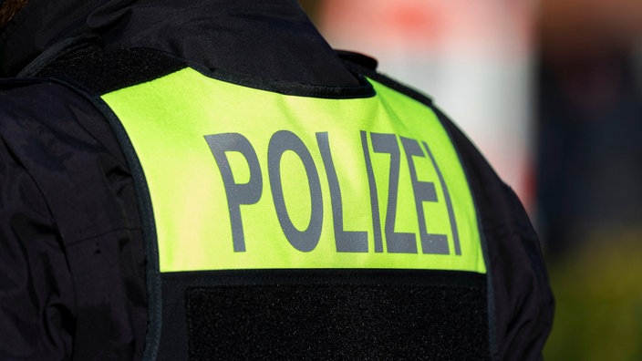 Symbolfoto: Der Schriftzug "Polizei" auf dem Rücken eines Polizisten.