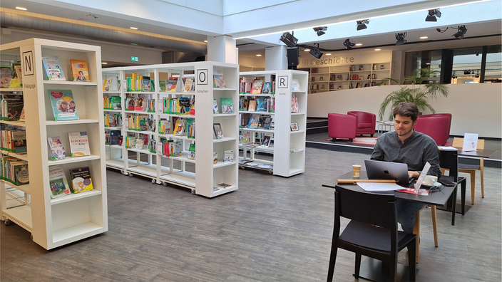 Ein Mann sitzt an einem Tisch in der Bibliothek.