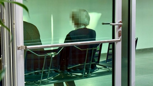 Die überfallene Rentnerin sitzt im Gerichtsflur auf einer Bank