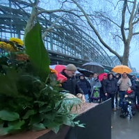 Menschen stehen am Mahnmal neben der Hohenzollernbrücke