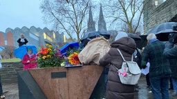 Eine Frau legt am Mahnmal einen Blumenstrauß nieder